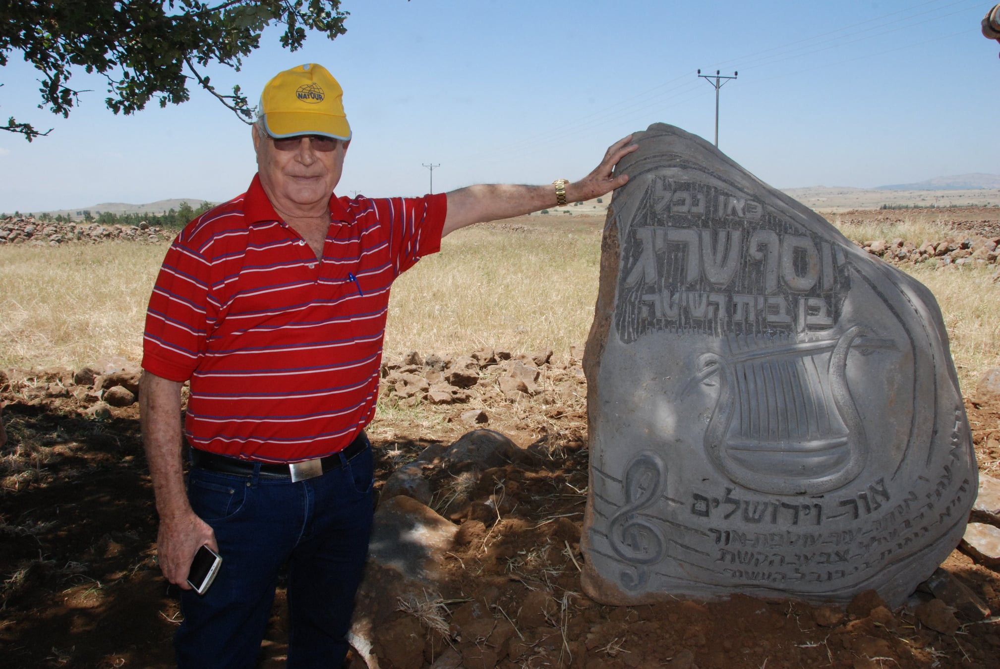 רן שריג ליד אבן זכרון לאחיו, יוסף, שהציב הפסל יובל לופן, במקום בו נפל, בחושניה. צילום: דוד {דדה} עינב